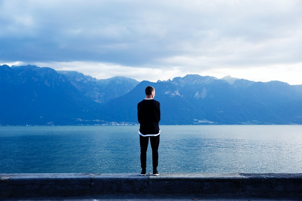 An image of a man thinking by a lake